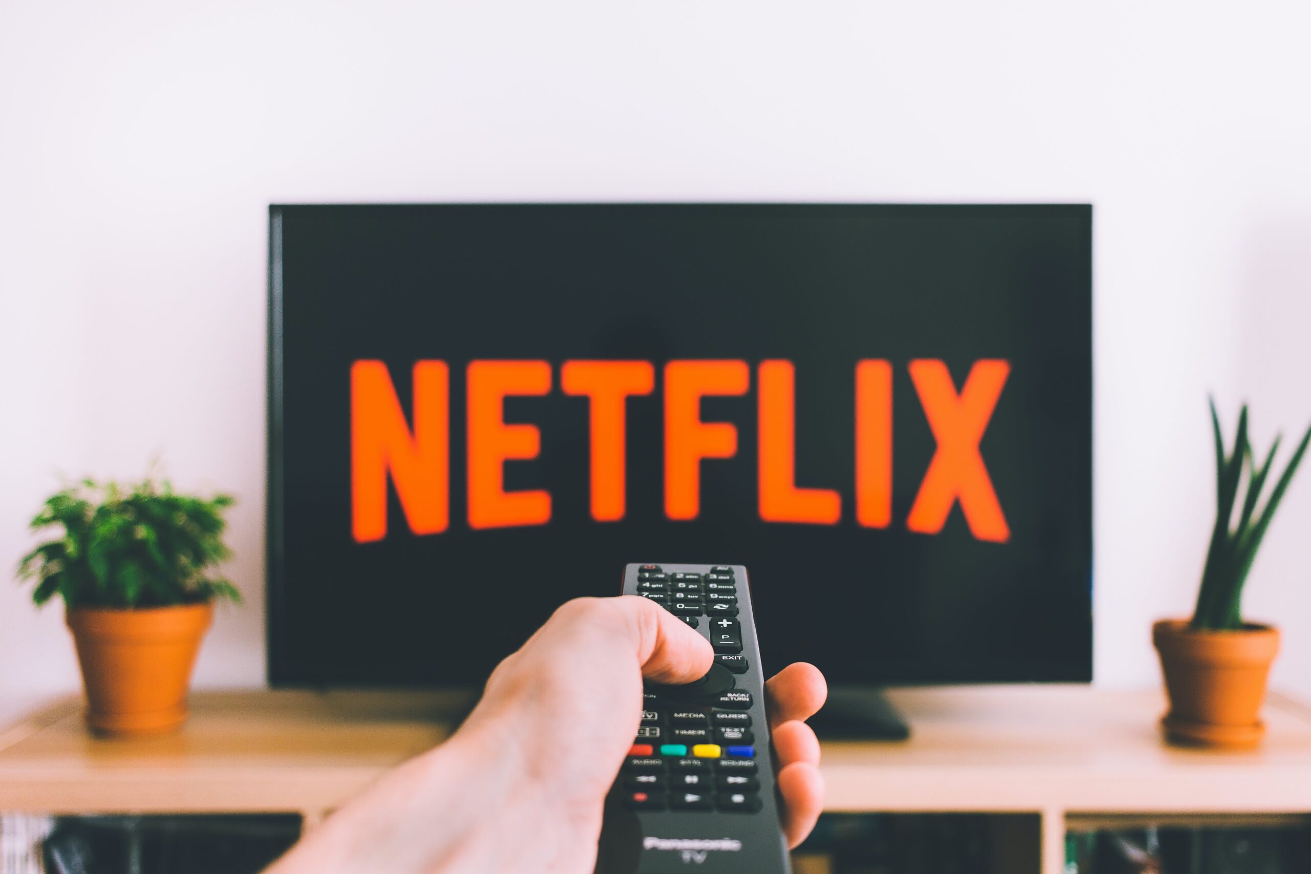 a person watching NTEFLIX while holding the TV remote in his hand